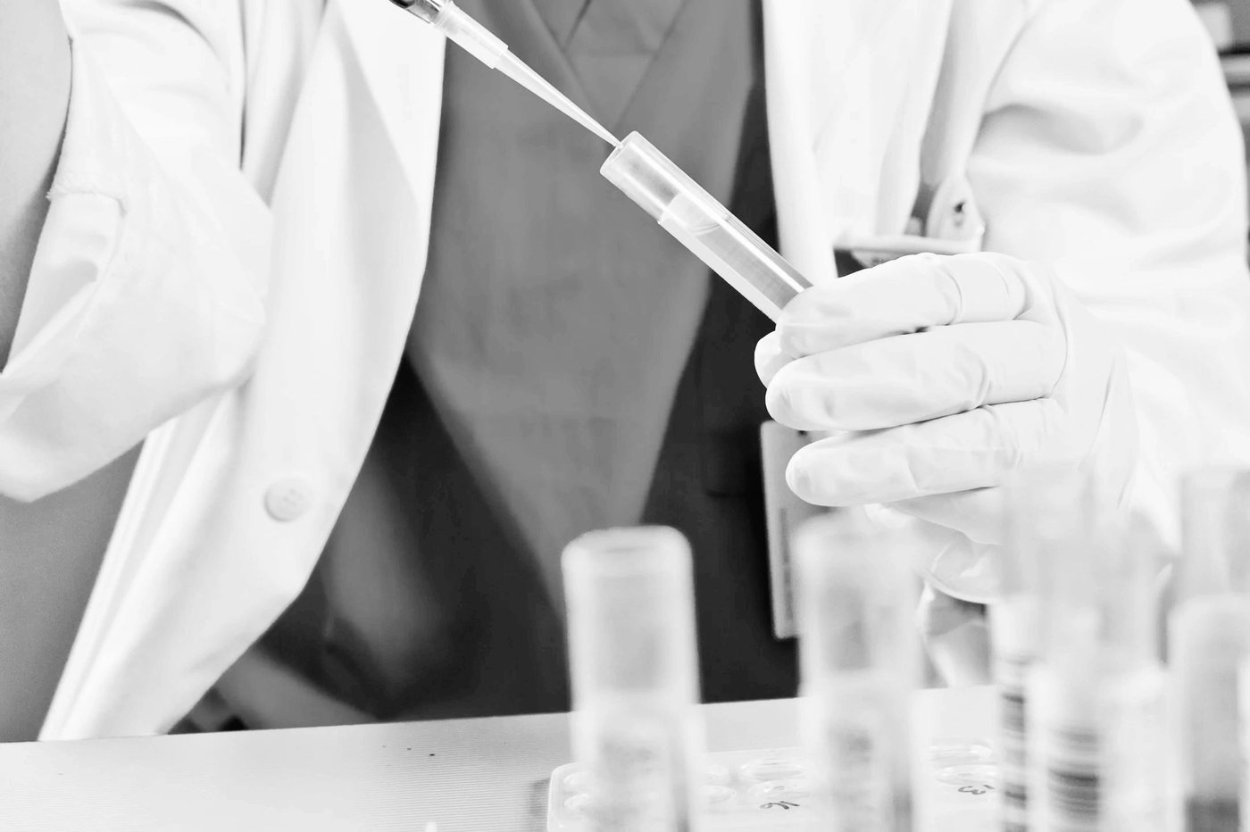 Researcher in a lab coat holding a test tube and pipette