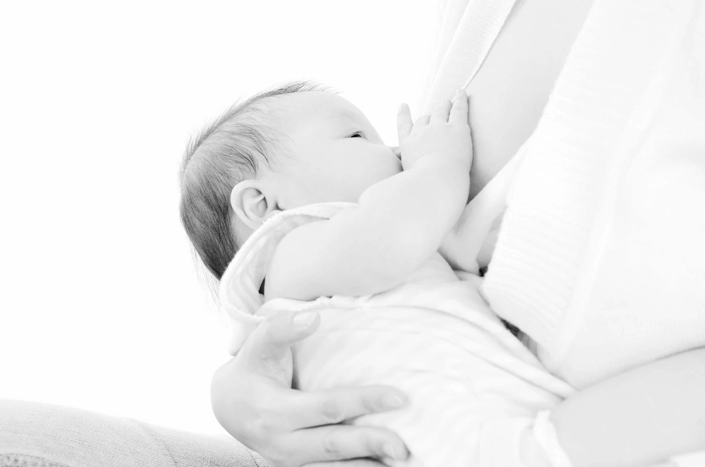 A baby breastfeeding, held gently by a caregiver